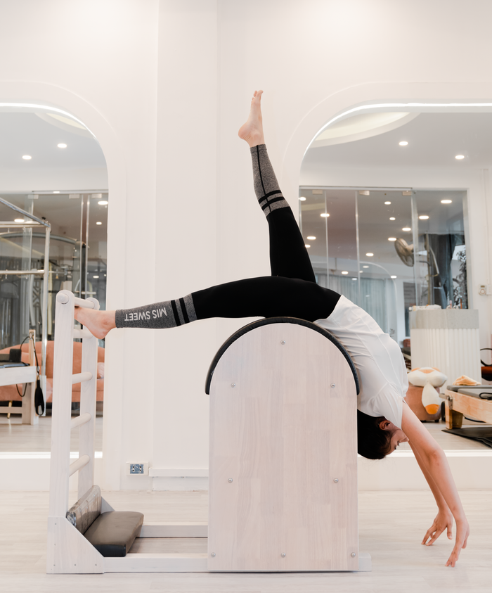 Woman engaged in pilates using specialized exercise equipment in a modern studio setting.