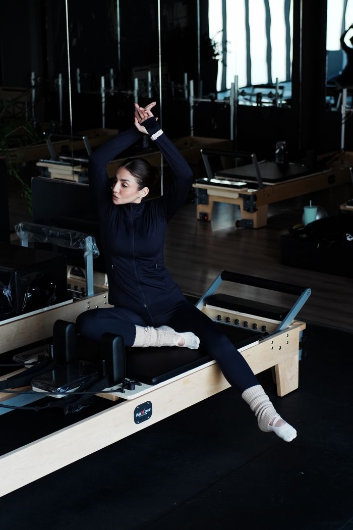 Woman performing Pilates on a reformer machine in a studio setting.