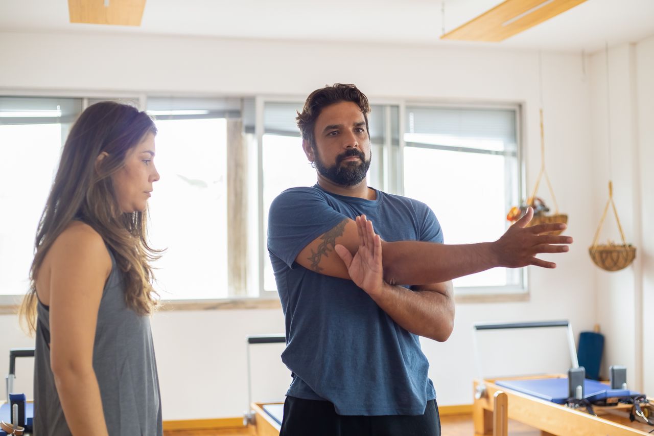 Man and woman during a training session focusing on stretching in a gym.